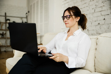 Middle aged business woman working at home using laptop