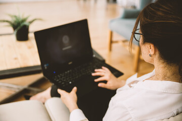 Over the shoulder view of middle-aged business woman working at home using laptop