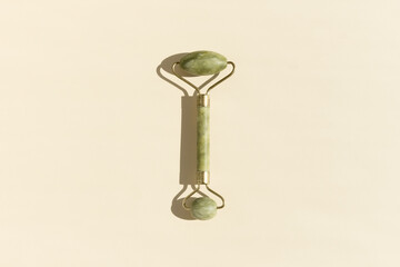 Jade Green Facial Massage Roller on a beige background. Skin Care Concept