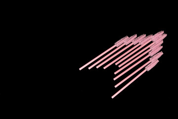 Pink eyelash brushes on a black background. Cosmetic accessories for eyelash extensions