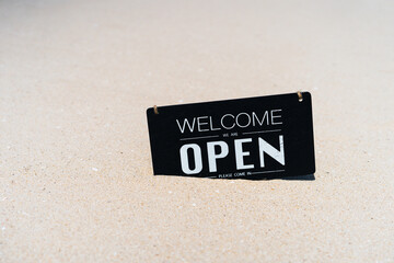 Open sign on tropical sand beach with blue sky background. Summer vacation and travel holiday concept.