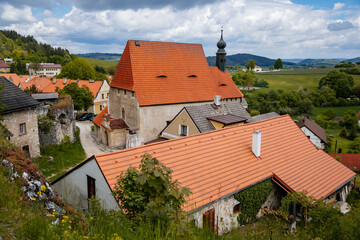 Village near ruins of gothic castle Rabi in National Park Sumava, Church of the Holy Trinity with a tower, landmark in countryside, red tiled roof, Rabi, Czech Republic