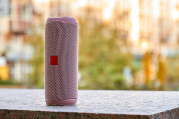 Portable pink wireless speaker in the city on granite surface. Close-up, selective focus
