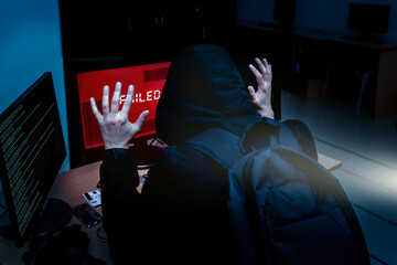 Internet criminal hacker trying to hack into corporate servers arrested by police at night. Portrait of a surrendered computer hacker who raised his hands under a flashlight. failed hack