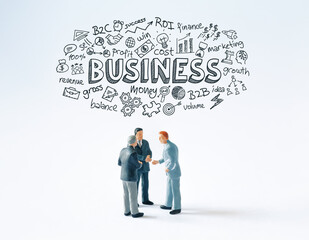 Developing a business strategy concept: Three business people figurines making a deal or talking about a project while hand drawn conceptual doodles and Business text above them. 