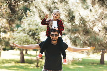 Dad and daughter relationship. Father with a child on his shoulders having fun outdoors. Adoption of a kid.