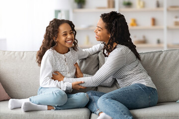 Cheerful black mother and daughter having fun together at home