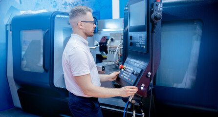 Worker man entering data in CNC machine at automatic factory floor. Modern process metal detail production going for car