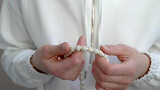 Japa meditation on the rosary. Hand-picking of wooden beads in close-up.