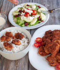 Side view family dinner with salad steam rice and breaded chicken on a table, vertical