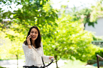 Fototapeta na wymiar Happy smiling woman rides a bicycle in the park. Beautiful woman enjoyung in the nature.