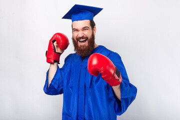 Photo of student man in blue bachelor and wearing red boxing gloves