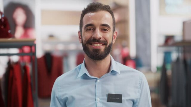 Portrait of a Happy Handsome Store Assistant in Blue Shirt Smiling and Posing for Camera at Clothing Store. Small Business Owner in a Role of a Businessman or Sales Manager.