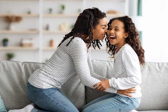 Happy african american mom tickling her laughing kid