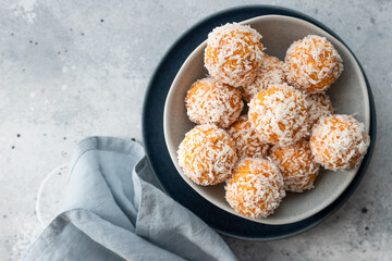 apricot coconut bliss balls in blue bowl. healthy raw vegan dessert. Gray background. top view