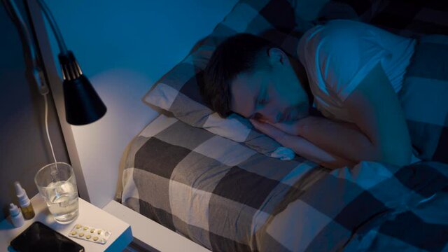 Depressed man lying in bed cannot sleep from insomnia. Young male trying to sleep. Restless worried guy wakes up at night lying on bed, sleepless, wide-eyed, suffering from insomnia, sleep disorder