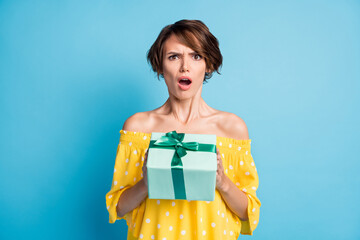 Photo of offended mad lady hold giftbox open mouth wear dotted yellow blouse isolated blue color background