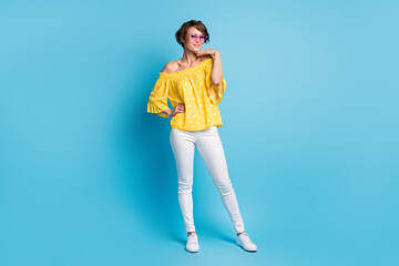 Fototapeta na wymiar Full length photo of stunning charming young lady wear white pants yellow dotted blouse isolated on blue color background