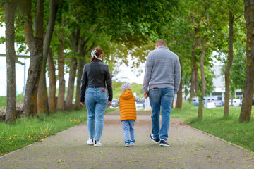 Happy family walking in the summer park and holding hands.