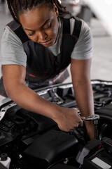 African woman car mechanic holding wrench checking up on the car engine, for repair and checkup,...