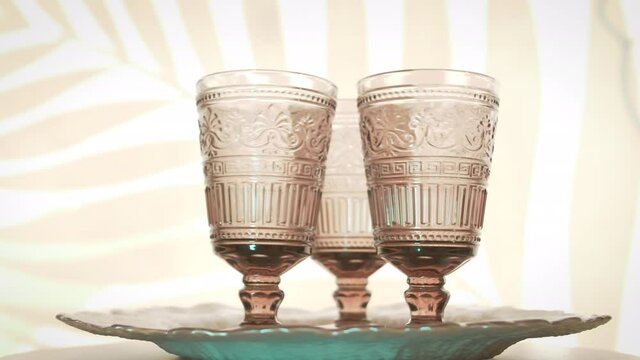 Three crystal wine goblets whirl on a tray.
