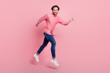Fototapeta na wymiar Full length photo of charming young happy man jump up run sale good mood isolated on pink color background