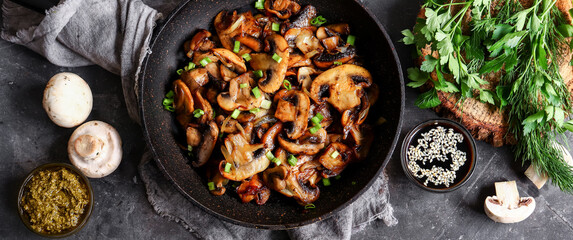 Roasted mushrooms with onion in frying pan on a dark background. Top view. Food banner - Powered by Adobe