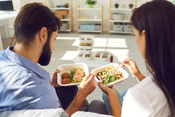 Young couple man and woman office workers sitting and enjoying healthy boxed food order delivered...