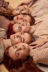 Obraz na płótnie Canvas Close-up portrait of caucasian redhead ladies feeling calmness and tenderness, laying down on floor in studio, side view. copy space. natural beauty, nude make-up concept
