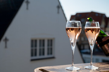 Drinking of rose champagne sparkling wine from flute glasses on outdoor terrace in France