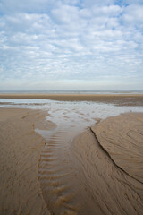 Low tide period on yellow sandy beach in small Belgian town De Haan or Le Coq sur mer, luxury vacation destination, summer holidays