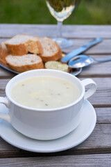 Lunch with homemade white asparagus soup and Dutch white wine served outdoor on green meadow with vineyard, asparagus and wine production farm in Netherlands