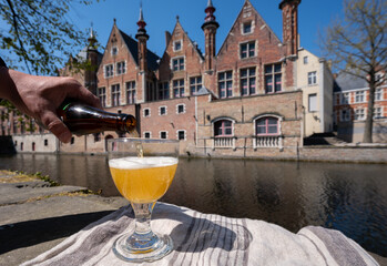 Fototapeta premium Tasting of Belgian beer on open cafe or bistro terrace with view on medieval houses and canals in Bruges, Belgium