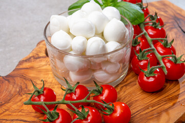 Italian tricolore, small balls of fresh white soft Italian mozzarella cheese, ripe red cherry tomatoes and fresh green basil herb, ready for making caprese salad