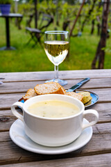 Lunch with homemade white asparagus soup and Dutch white wine served outdoor on green meadow with vineyard, asparagus and wine production farm in Netherlands