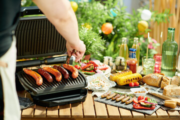 table with electric grill and grilled sausages