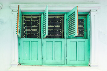 Antique wooden window frame, turquoise windows and the white Wall