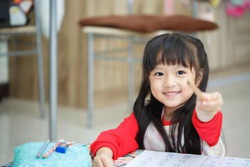 Asian little girl learning and writing in notebook with pencil