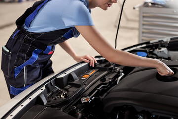 Fototapeta na wymiar Female auto mechanic examine car engine breakdown problem in front of automotive vehicle car hood. Safety technical inspection care check service maintenance for customer before long road trip