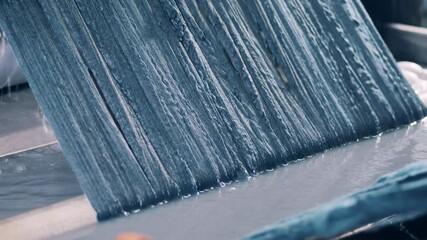 Strands of yarn are emerging from coloured water