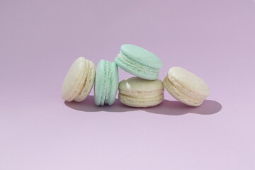 Pastel yellow and blue sweet macaroons on violet background. Homemade baked cookies with sugar.