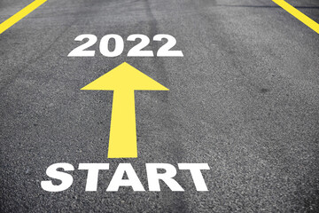 Start to 2022 and yellow arrow on asphalt road surface. Business challenge concept and keep going idea