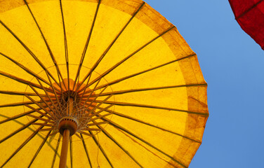 Under  side of yellow handmade paper umbrella with blue sky.