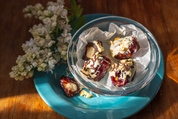 Homemade date candies with nuts, covered with white chocolate and decorated with chopped nuts.