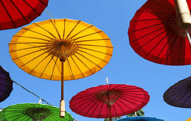 Under side of yellow handmade paper umbrella and others with blue sky background. 