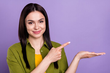 Photo of sweet shiny young woman wear khaki outfit smiling pointing holding arm empty space isolated violet color background