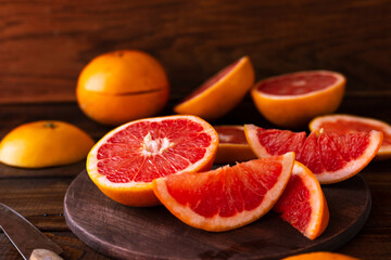 Naklejka na ściany i meble sliced pieces of grapefruit lie on the table on the dark wooden countertop