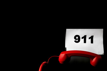 Call 911 and emergency call concept, text 911 on paper and phone isolated on black.