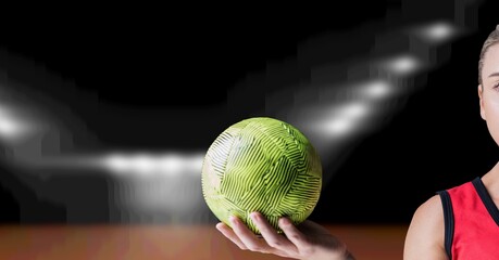 Composition of hand of female volleyball player holding ball over blurred indoor court background