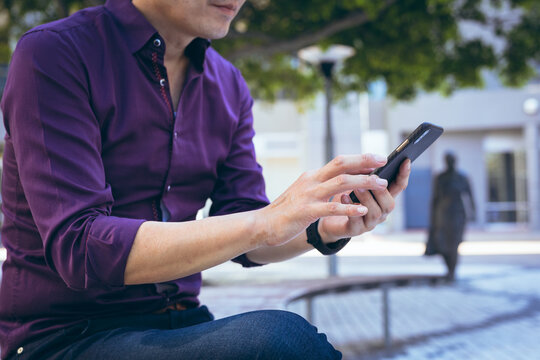 Midsection of asian businessman using smartphone in city street